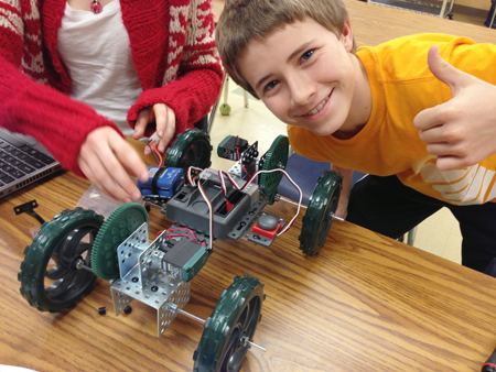 Eighth grader proudly displays robot he helped build during Fritz's Project Lead the Way unit.